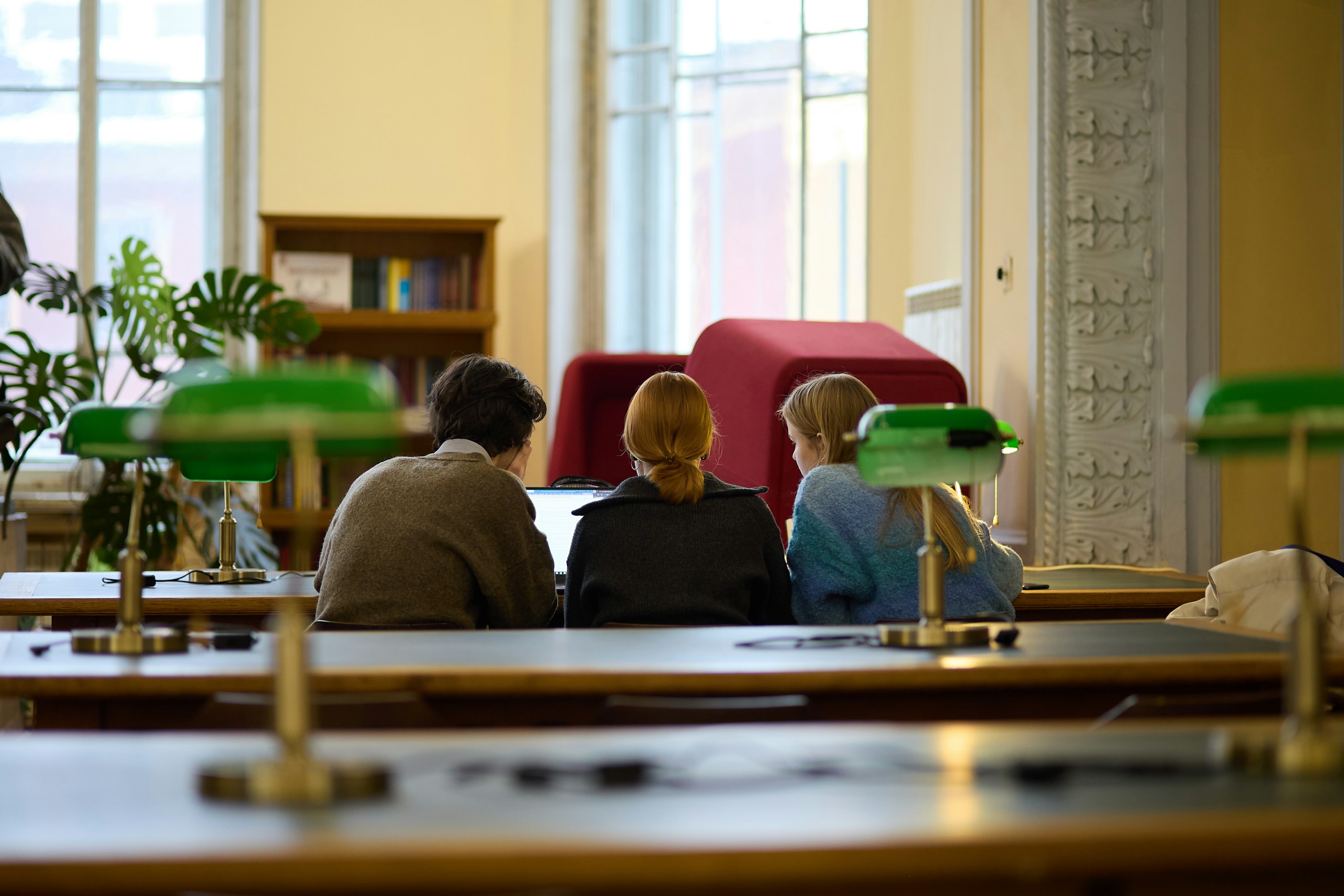 A university library reading room with students studying at desks